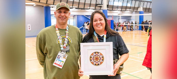 A man with a woman holding a picture frame in a gym